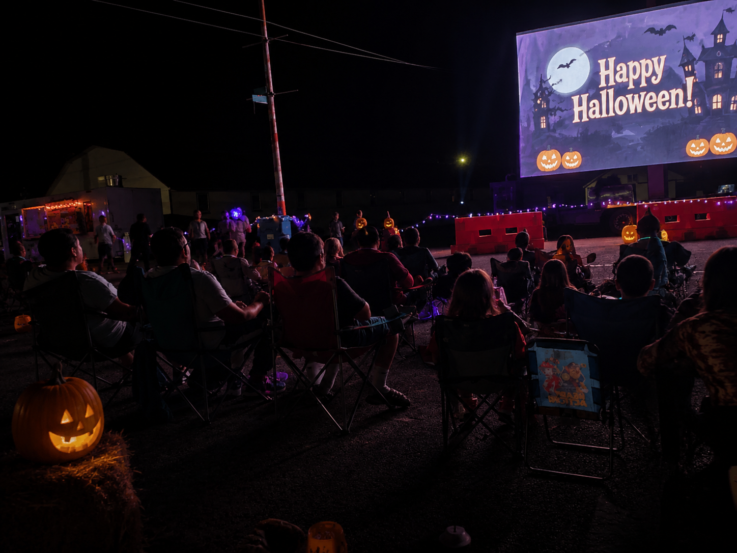 Outdoor movie screen, families and Halloween lights
